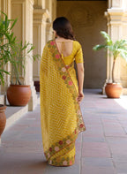 Woman wearing a yellow saree with floral patterns yellow